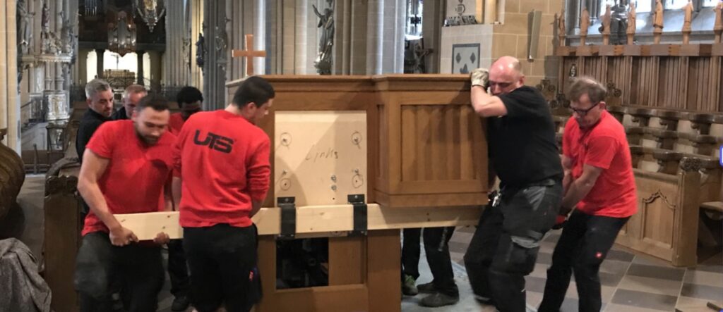 Mitarbeiter heben den Generalspieltisch der Domorgel Paderborn an und bereiten ihn für den Transport vor